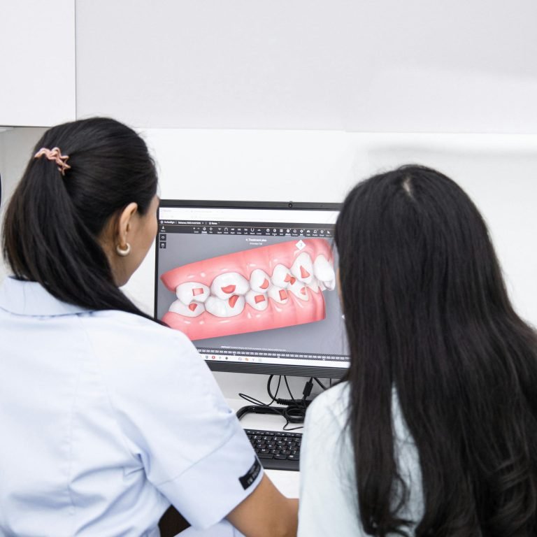 Dentists analyzing a 3D dental model on a computer for patient consultation.